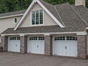 A large home with stone siding has three garage doors.