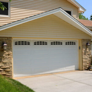 close up view of a large, white garage door on a cream colored two-story home
